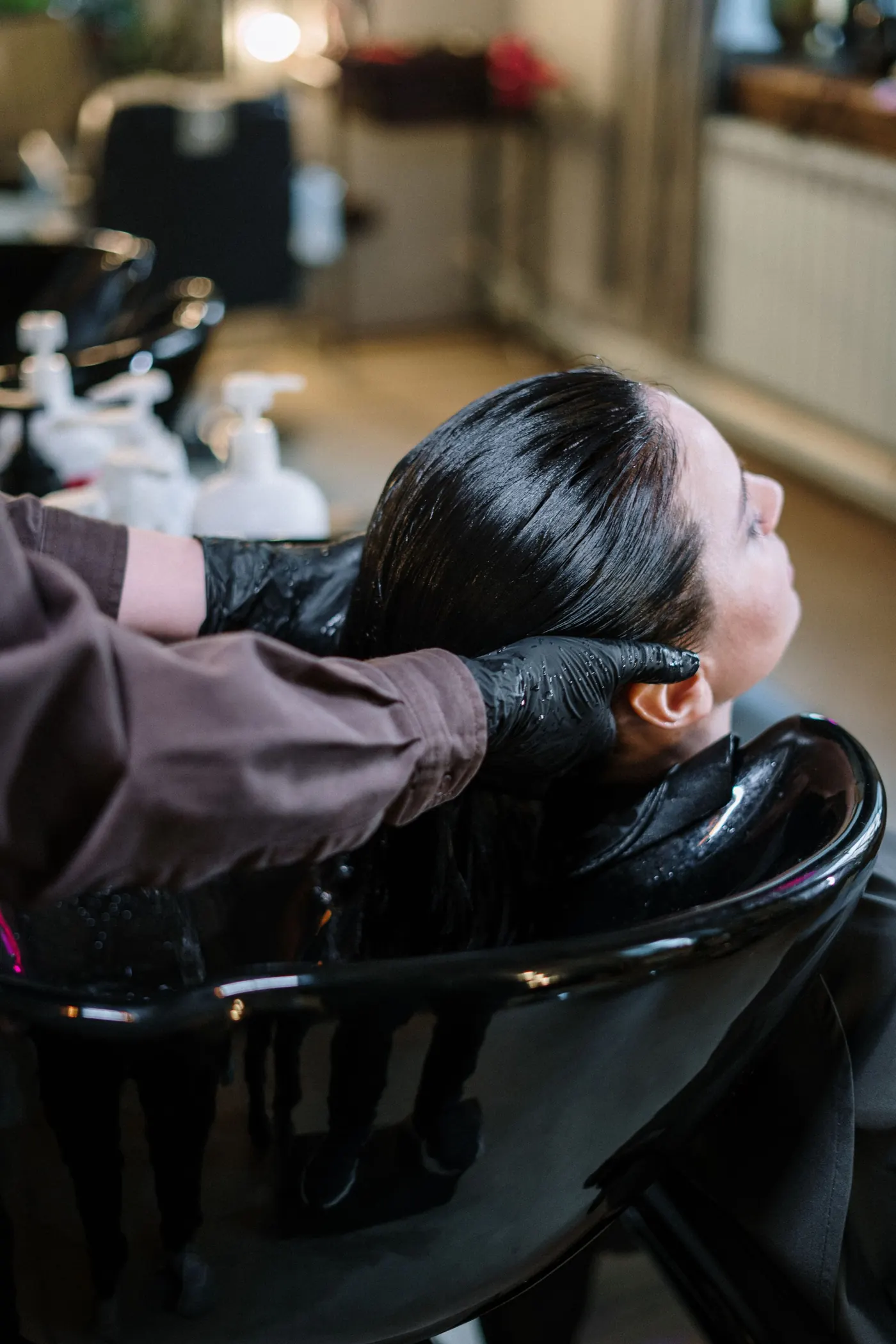 Cliente de cabelo longo e escuro relaxando no lavatório do salão