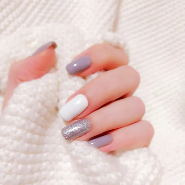 Unhas esmaltadas em tons claros sobre tricô branco